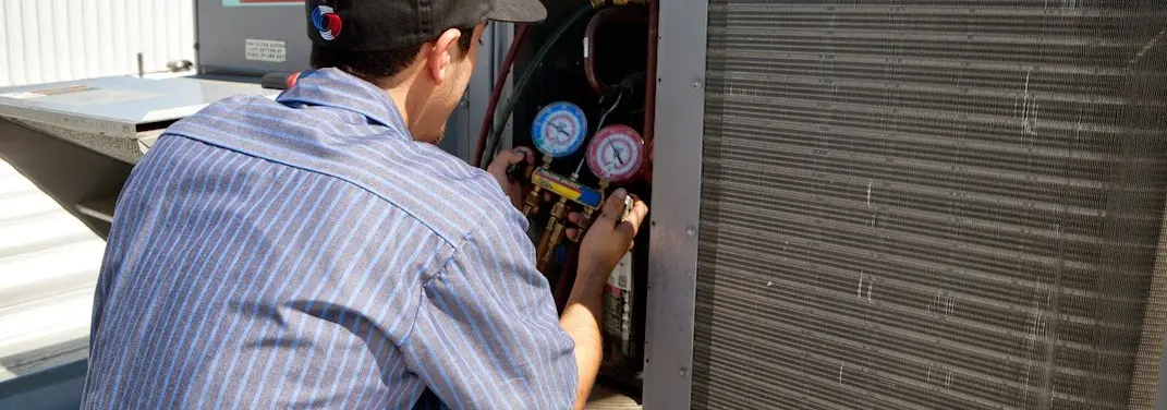 HVAC technician servicing a condenser unit in Hilmar-Irwin